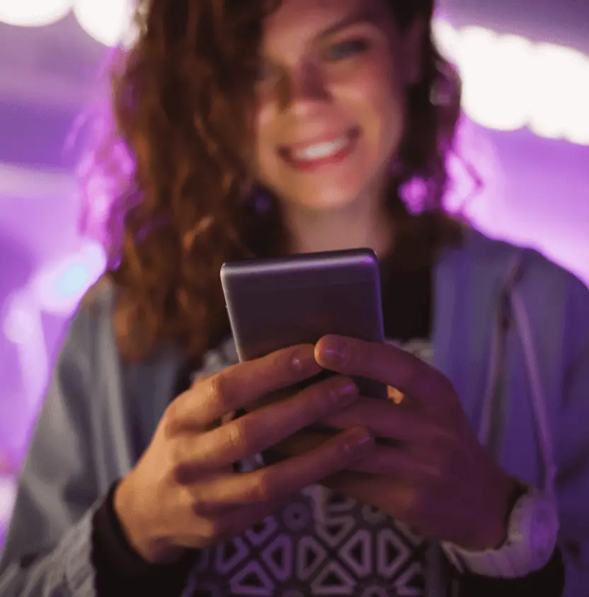 Mujer sosteniendo un celular en sus manos y sonriendo