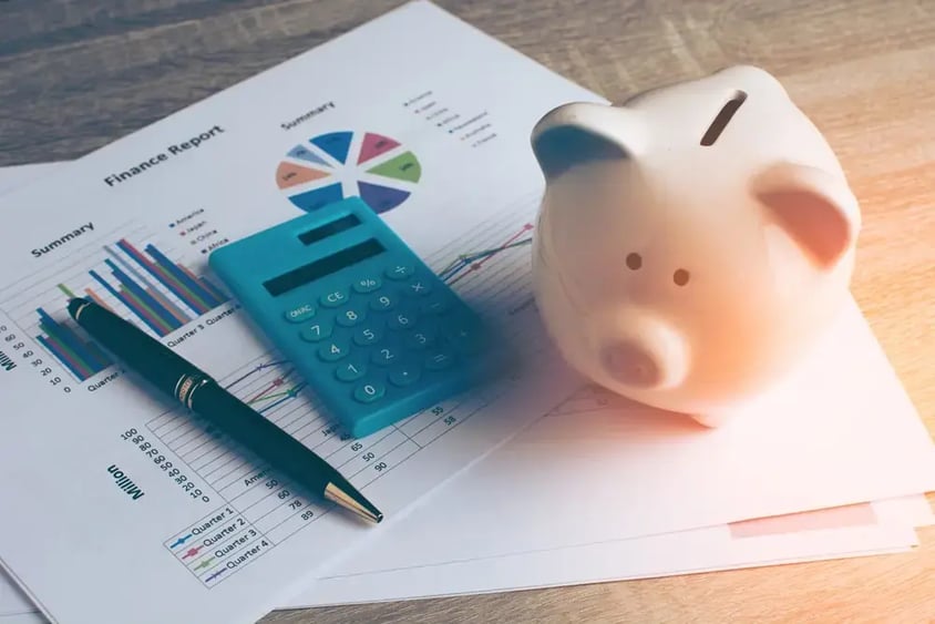 Alcancía, calculadora e informe de ahorros sobre un escritorio
