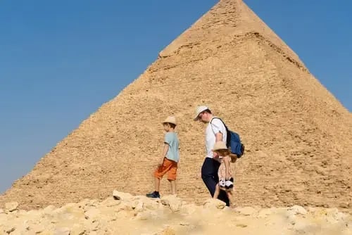 un padre y su hija e hijo caminando alrededor de una pirámide en Egipto