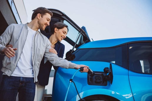 Mujer joven consultando una aplicación móvil para monitorear la carga de un auto eléctrico en Colombia.