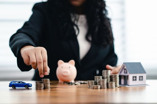 Vista de cerca de una mujer concentrada apilando monedas junto a una alcancía, simbolizando el proceso de calcular los activos financieros para el patrimonio personal.