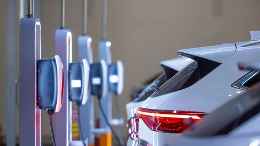 Fila de autos eléctricos e híbridos enchufables cargando sus baterías en una estación de servicio moderna en Colombia.