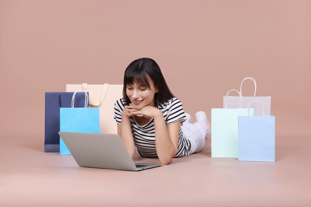 Mujer realizando compras en línea de forma segura desde su laptop en tiendas virtuales.