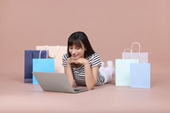 Mujer realizando compras en línea de forma segura desde su laptop en tiendas virtuales.