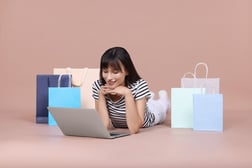 Mujer realizando compras en línea de forma segura desde su laptop en tiendas virtuales.
