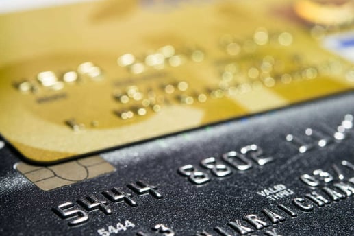 Primer plano de una persona sosteniendo una tarjeta de crédito frente al teclado de una computadora portátil mientras realiza una compra online segura en comercio electrónico.