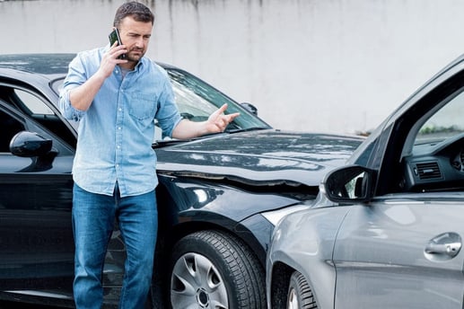 Conductor preocupado reportando un choque de carro y revisando los daños para la reclamación de su seguro vehicular.