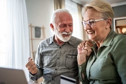 Pareja de pensionados sonrientes revisando las ventajas y tasas bajas de un crédito de libranza.