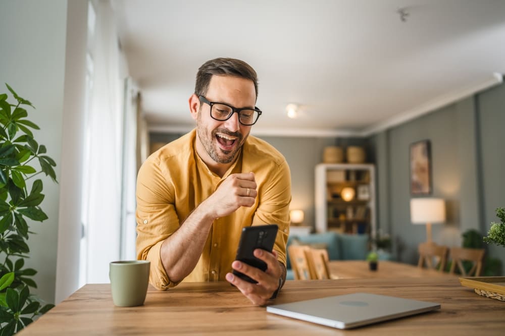 Hombre con barba sonriendo mientras descarga su certificado bancario digital desde la aplicación móvil de su cuenta de ahorros Finandina.