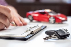 Hombre firmando el contrato de compraventa y revisando los documentos legales para comprar un carro usado.