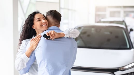 Mujer joven y feliz sosteniendo la llave de su automóvil, ilustrando la decisión de comprar un carro nuevo o usado en Colombia.