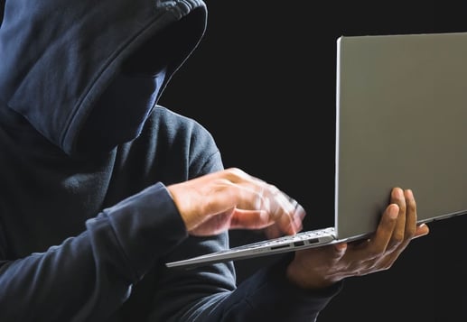 Manos de un ciberdelincuente frente a un computador, representando los fraudes en línea y estafas digitales con el SOAT digital.