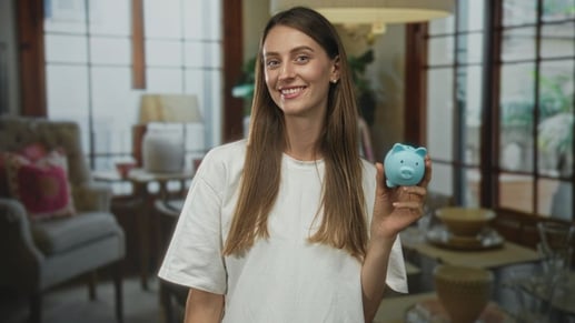 Mujer sonriendo sosteniendo una alcancía como símbolo de hábito de ahorro e inversión a largo plazo.