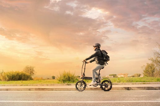 Hombre sonriente con casco protector preparándose para conducir su bicicleta eléctrica urbana.