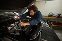 Mecánico realizando una inspección visual al motor de un carro usado antes de su compra.