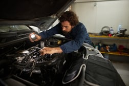 Mecánico realizando una inspección visual al motor de un carro usado antes de su compra.
