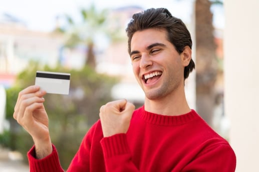 Joven sosteniendo una tarjeta de crédito, primer paso para construir su historial crediticio