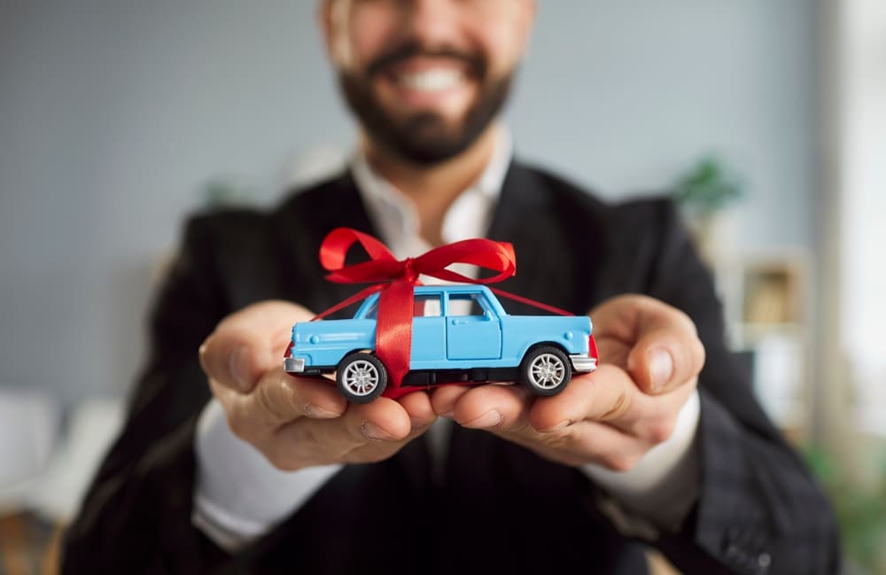 Hombre sosteniendo un carro de juguete tras finalizar su crédito y tramitar el levantamiento de prenda vehicular.