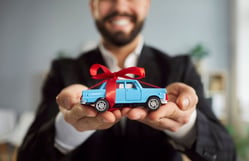 Hombre sosteniendo un carro de juguete tras finalizar su crédito y tramitar el levantamiento de prenda vehicular.
