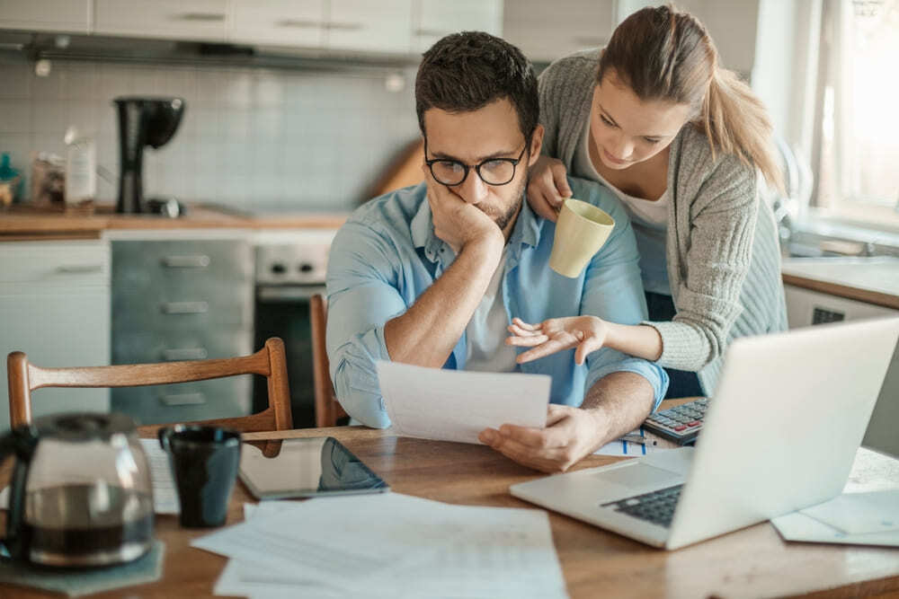 Pareja revisando sus finanzas personales en computador para organizar un plan de pago de deudas.