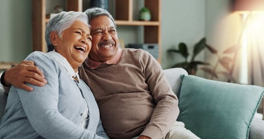 Pareja de adultos mayores pensionados sonriendo en su casa tras cumplir los requisitos para pensionarse en Colombia.