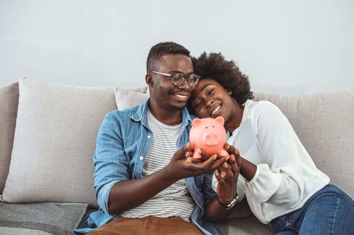 Pareja joven sonriente en su hogar organizando su planificación financiera y usando una plantilla de ahorro mensual.