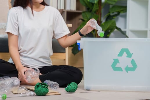 Mujer separando botellas de plástico en casa demostrando el hábito del reciclaje en Colombia.