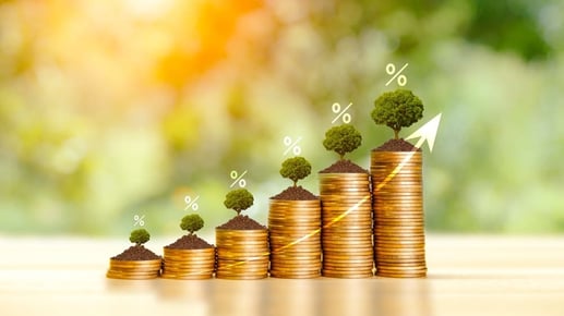 Monedas apiladas sobre una gráfica que representa el rendimiento financiero y el ahorro a largo plazo.