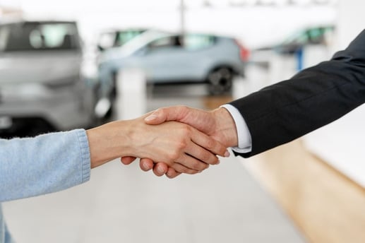 Vendedor y comprador dándose la mano tras cumplir con los requisitos para hacer el traspaso de un vehículo.