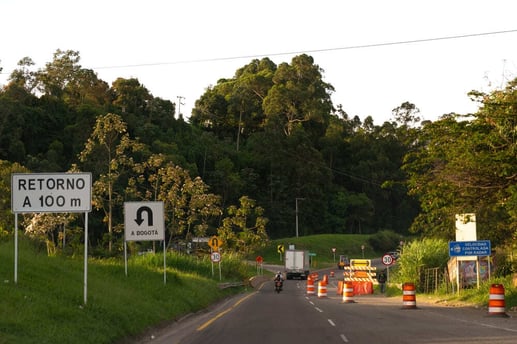Señales de tránsito informativas en una carretera colombiana que sirven como guía de orientación para un retorno y la ruta hacia Bogotá.