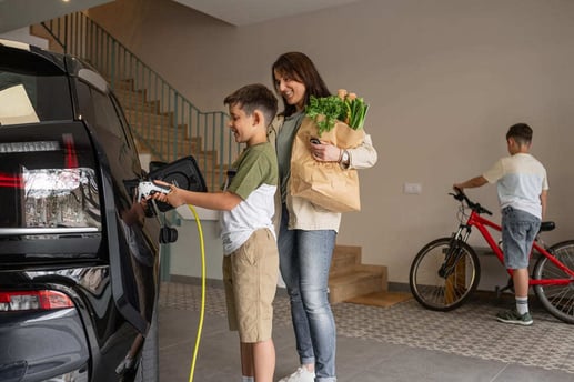 Madre e hijo sonriendo mientras conectan el cable de carga a un carro híbrido enchufable (PHEV).