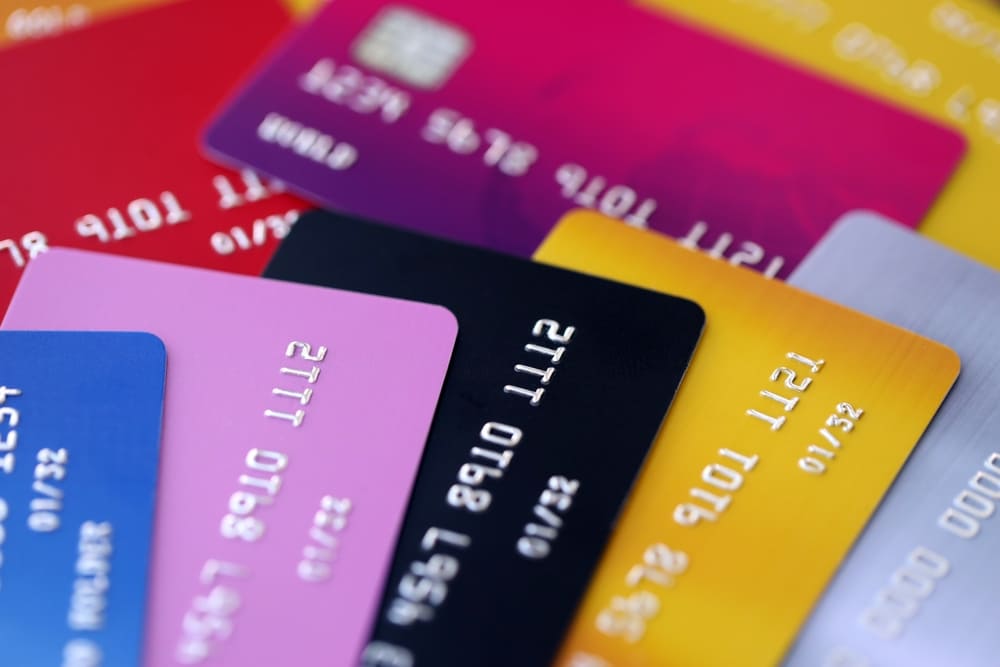 Colección de múltiples tarjetas de crédito, débito y prepago de diferentes colores dispuestas en abanico para comparar productos financieros.