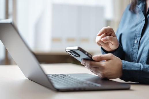 Persona utilizando una computadora portátil y un teléfono inteligente para hacer un envío de dinero en línea de forma segura.