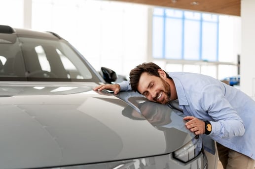 Propietario feliz abrazando su automóvil luego de dejarlo libre de prenda vehicular y limitaciones en el sistema de tránsito.