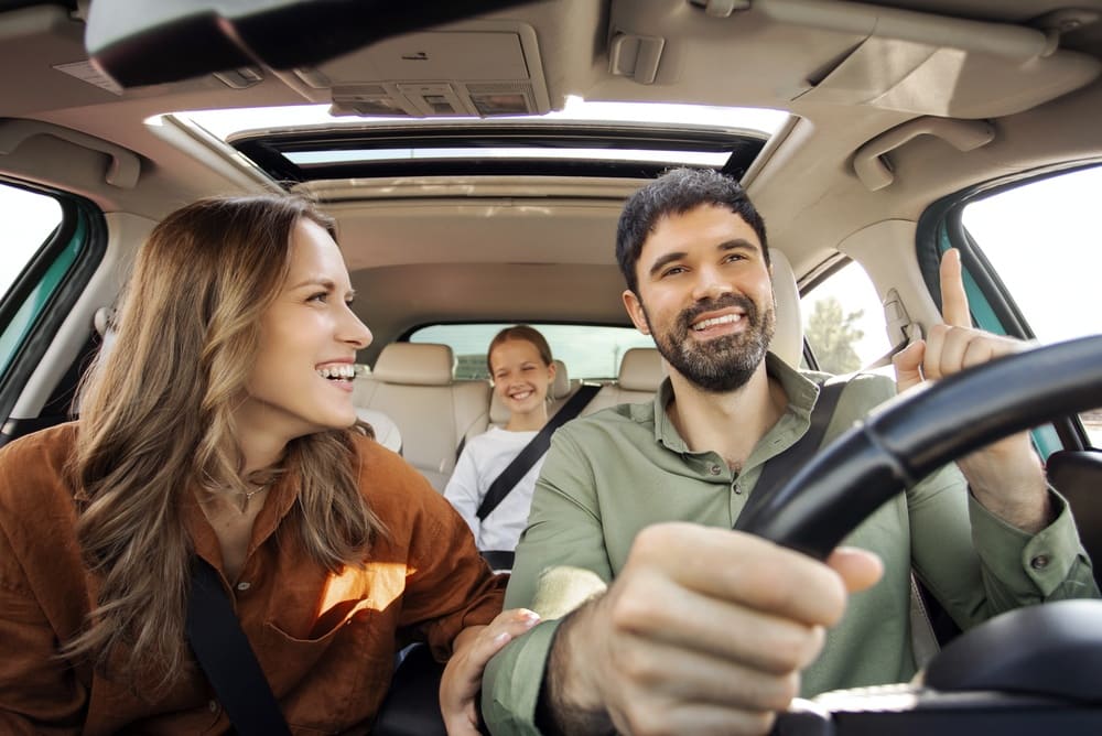Pareja sonriente disfrutando de un viaje en carretera, representando la decisión inteligente entre elegir un auto nuevo o un usado.