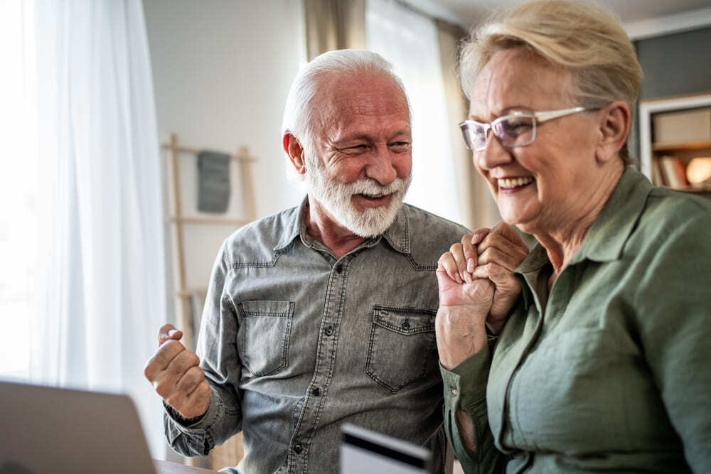 Pareja de pensionados sonrientes revisando las ventajas y tasas bajas de un crédito de libranza.