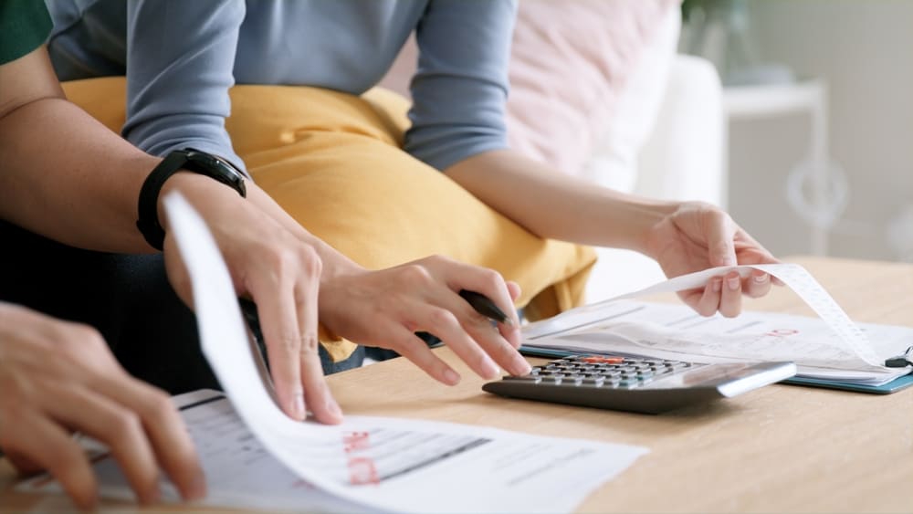 Persona analizando su presupuesto mensual y comparando opciones entre una cuenta de ahorros de alto rendimiento y una cuenta corriente.